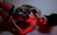 a woman with tattoos and lingerie laying on the floor