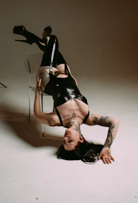 a woman in latex is doing a handstand on a chair