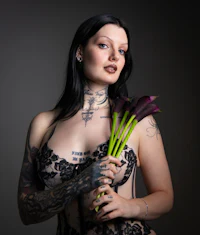 a woman with tattoos holding a bouquet of flowers