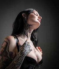 a woman with tattoos posing on a dark background