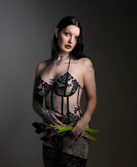 a woman in black lingerie holding flowers